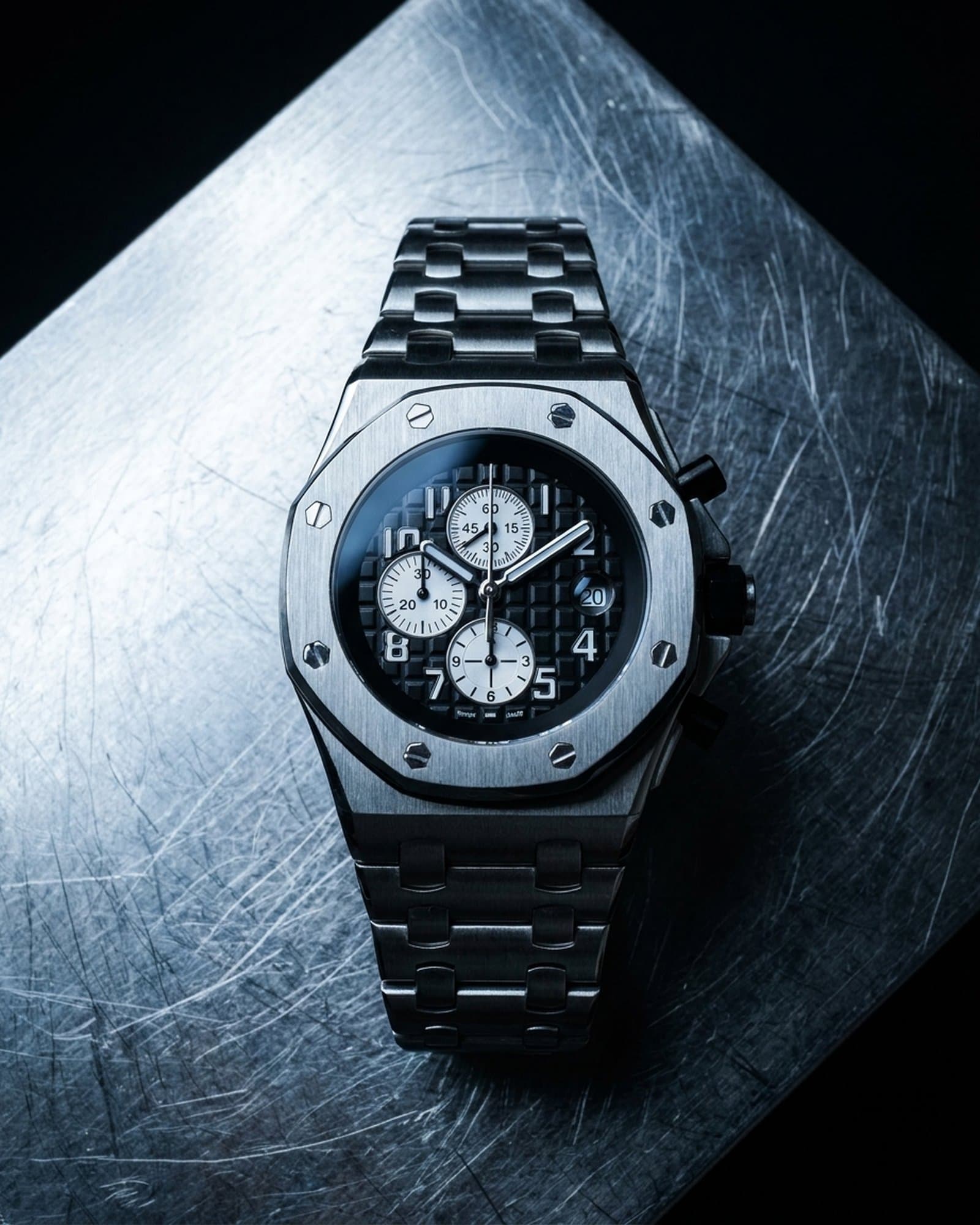 Octagon chronograph with a black dial lying on scratched steel under a cold light
