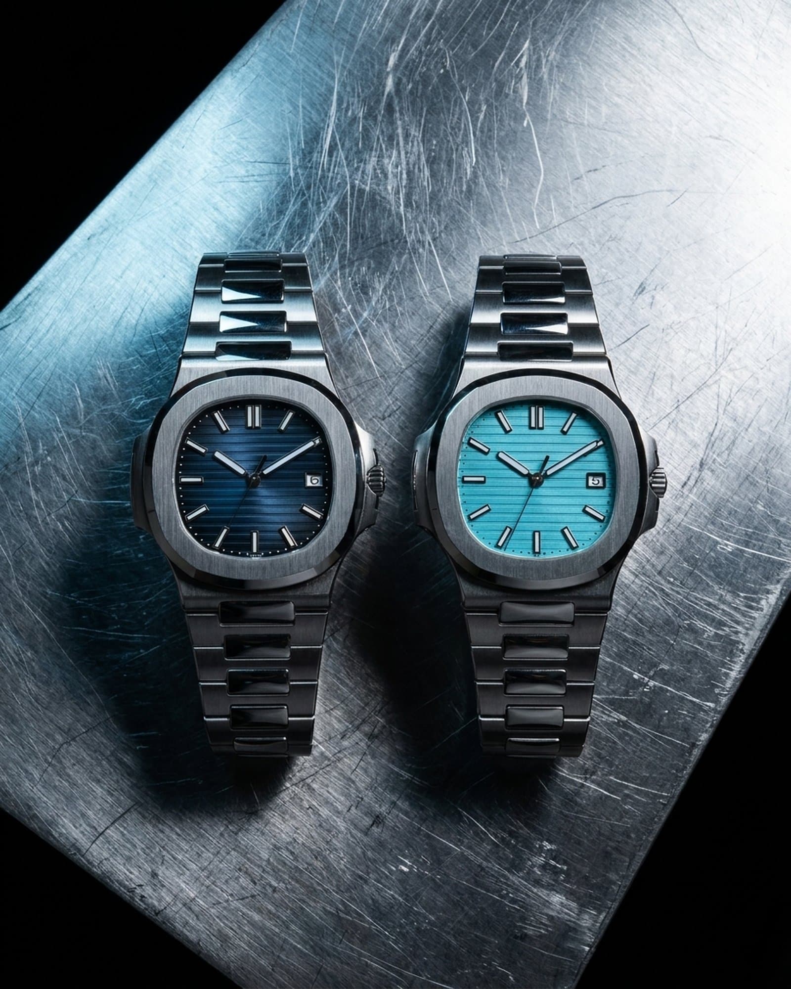 Two steel sport watches, blue and turquoise dials, side by side on scratched steel
